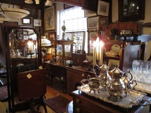 A cozy antique shop filled with vintage furniture, art, and silverware.