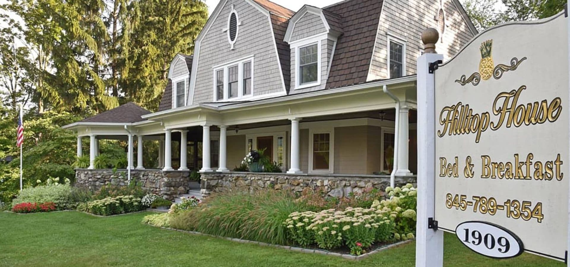 Exterior of Hilltop House Bed & Breakfast surrounded by greenery and flowers.