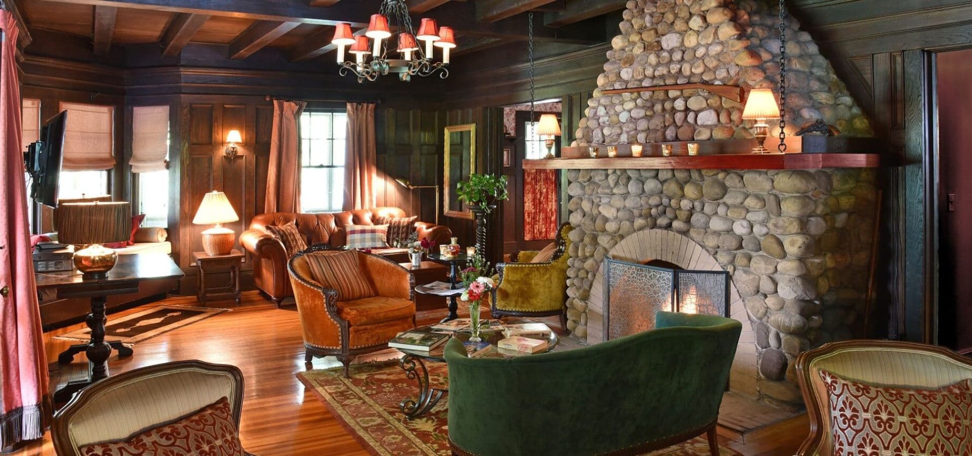 Cozy living room with a stone fireplace, wooden beams, and elegant furniture.